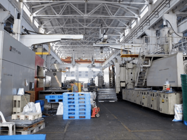 A factory with large machinery and blue plastic pallets, showcasing the production scale of top 5 plastic pallet manufacturers in Russia.