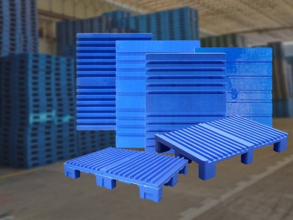 A stack of blue plastic pallets in various orientations, set against a backdrop of a warehouse filled with similar pallets, highlighting the manufacturing prowess of top producers in Bhutan.