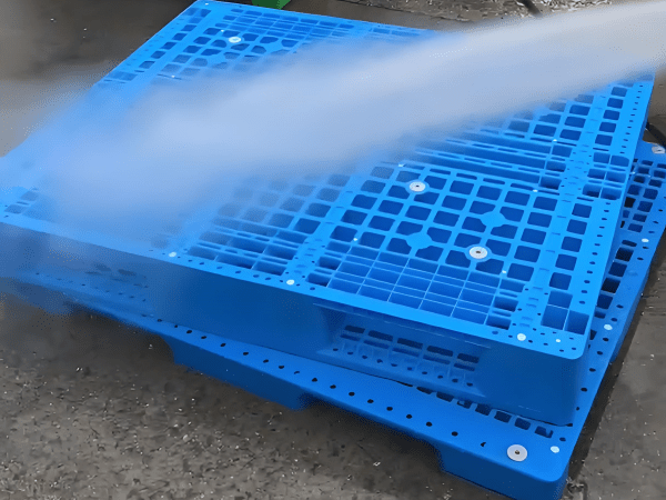 In the factory, the press washer is washing the double-sided grid pallet