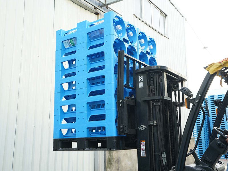 A blue plastic water rack being lifted by a forklift, showcasing its four - way entry design for forklift access at the base.