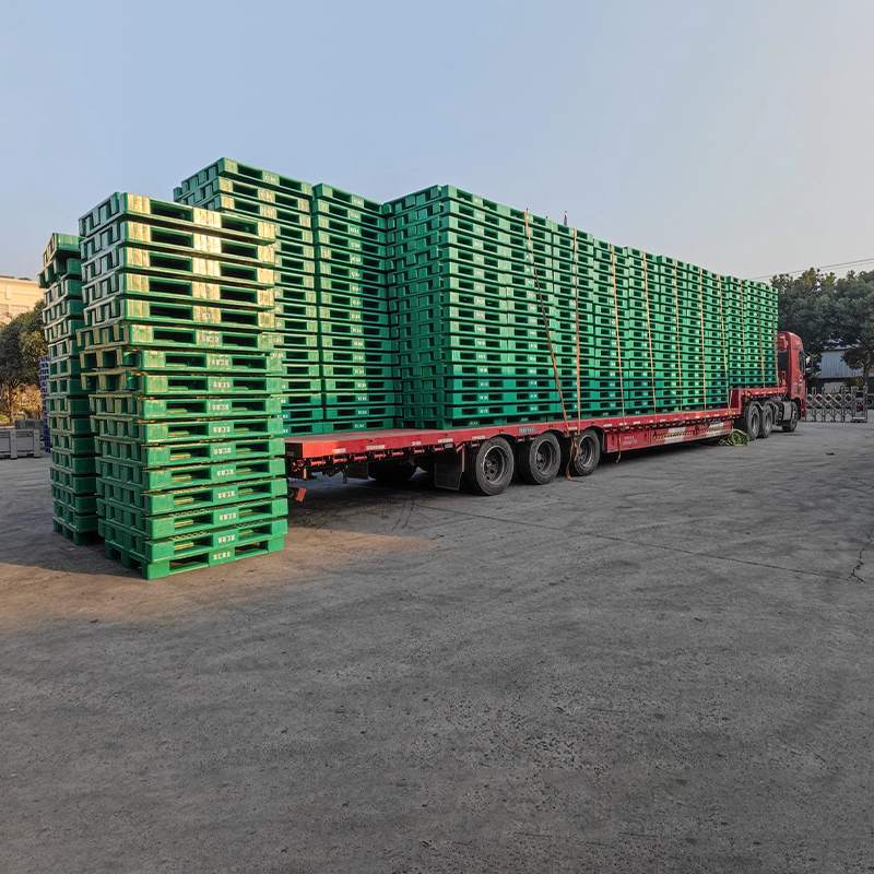 Truck loaded with green pallets. Our global shipping arranges logistics for plastic pallets as per your preference.