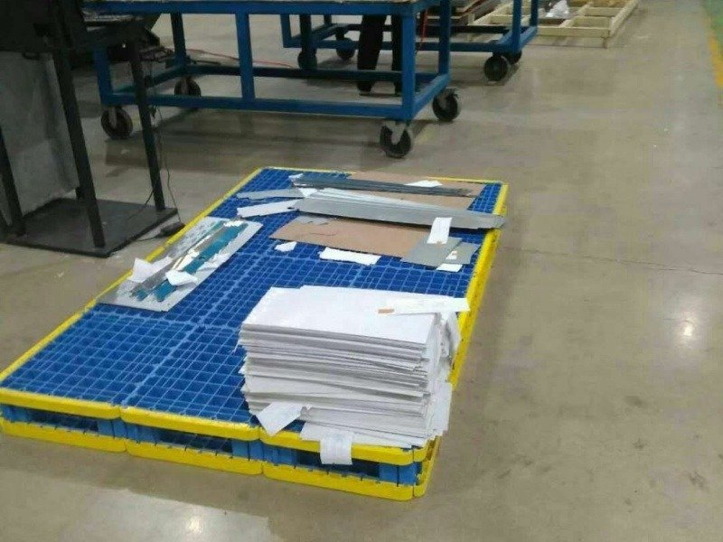 The blue and yellow plastic trays in the factory are filled with piles of paper and metal plates, and our workers are carrying out customized designs.