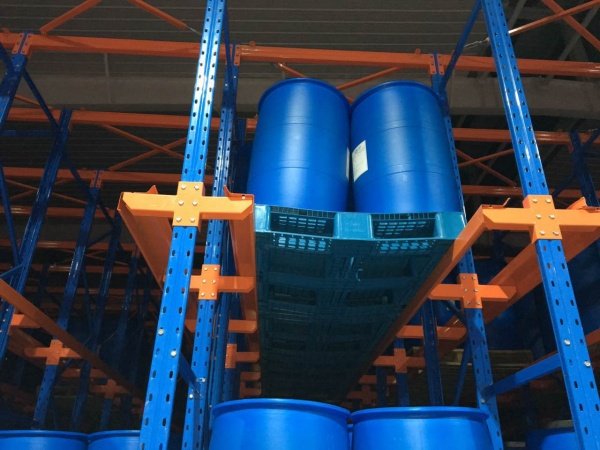Blue barrels on pallet in warehouse racking, showing storage setup for safety and load limit info.