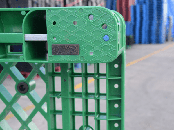Green gird plastic pallet corner, showing structural details, for logistics use.