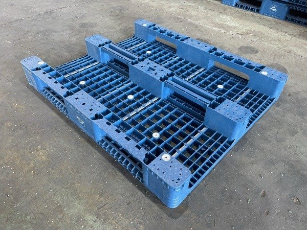 Blue 3 runners plastic pallet with grid design, placed on warehouse floor, for stacking.