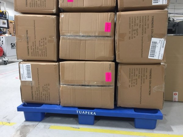 Nine paper boxes containing goods are stacked on a blue nine legged nested plastic pallet