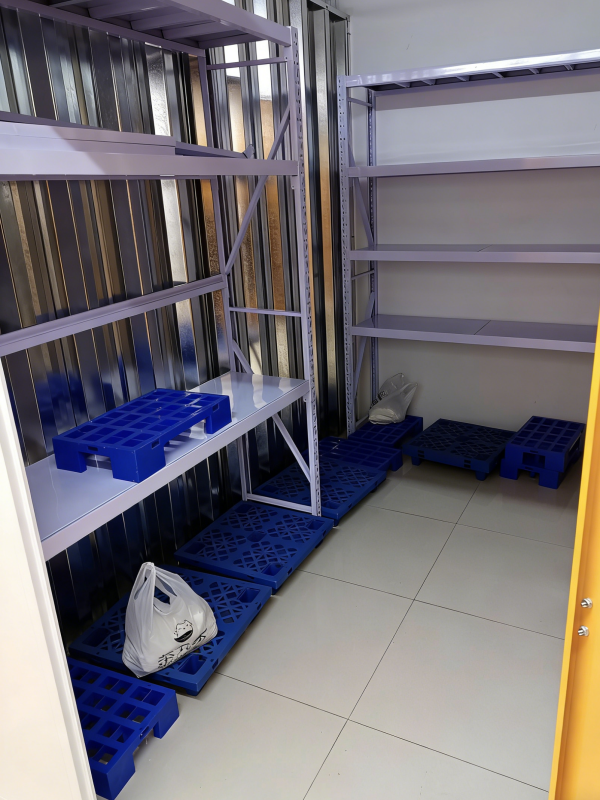 blue plastic floor pallets used in small storage room with shelving